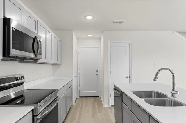 a view of a kitchen with stainless steel appliances granite countertop a sink and a refrigerator
