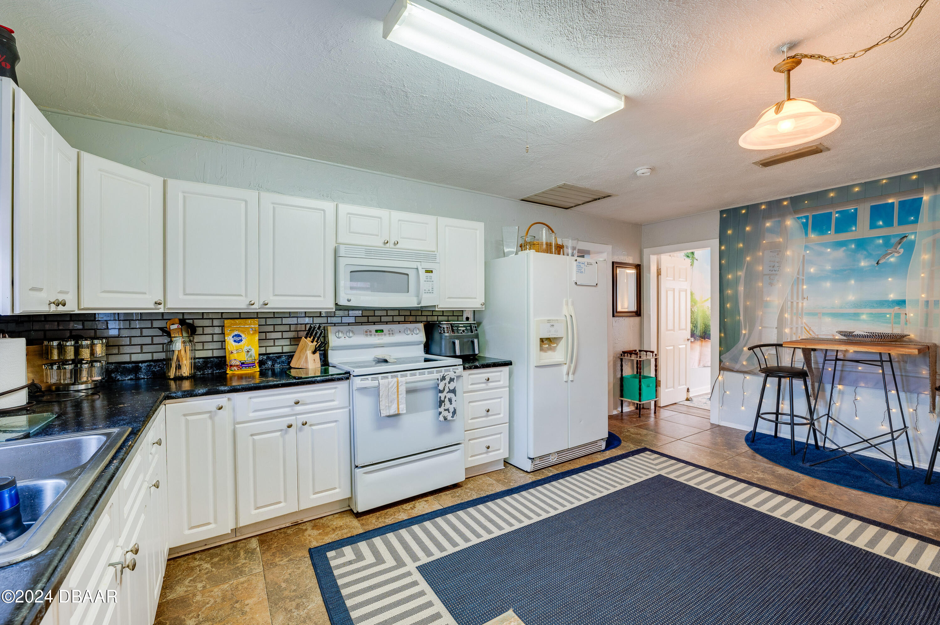 4850 Spruce Creek Road Port Orange, FL 32127 - Photo 9 of 27 a kitchen with white cabinets and appliances