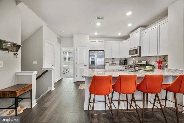 a large kitchen with kitchen island white cabinets and stainless steel appliances