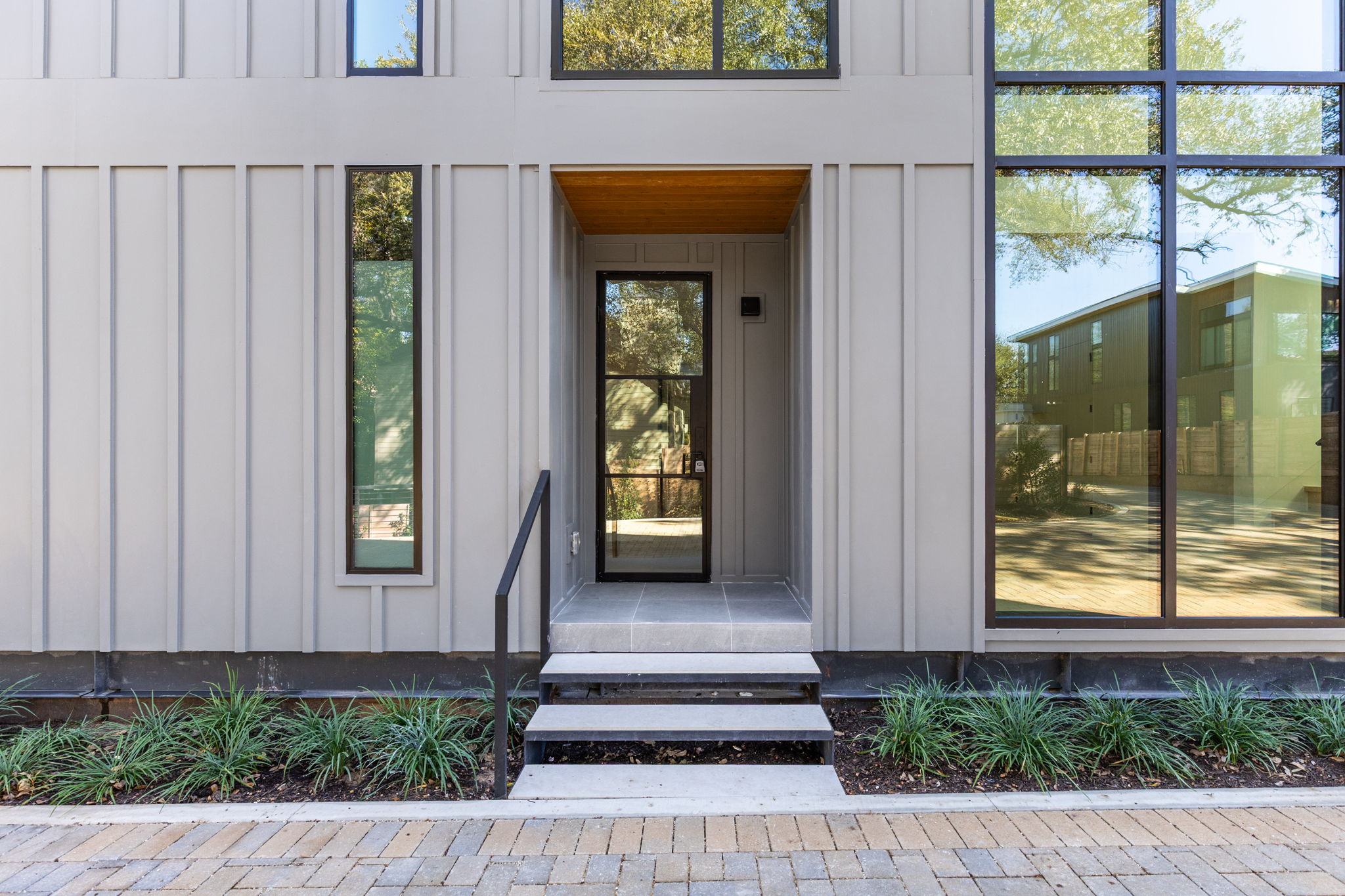 1603 Chelsea Lane, Unit 1 Austin, TX 78704 - Photo 3 of 34 A modern glass front door welcomes visitors with sleek vertical siding and towering windows.