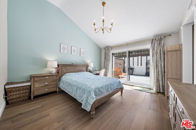 a bedroom with a large bed a chandelier and dresser
