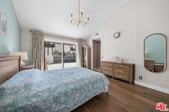 a spacious bedroom with a bed and dresser with wooden floor