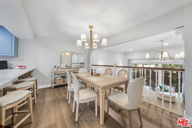 a dining room with wooden floor a chandelier a wooden table and chairs