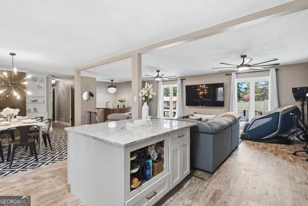 a large living room with stainless steel appliances granite countertop couches a flat screen tv and a stove