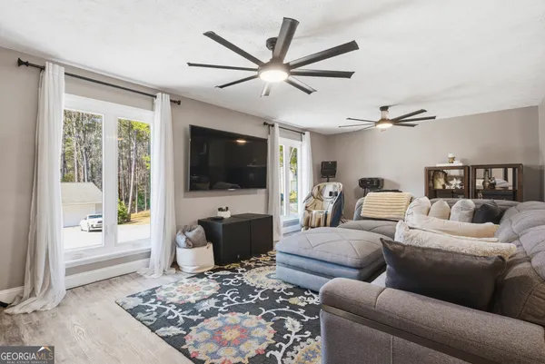 a living room with furniture a flat screen tv and a large window