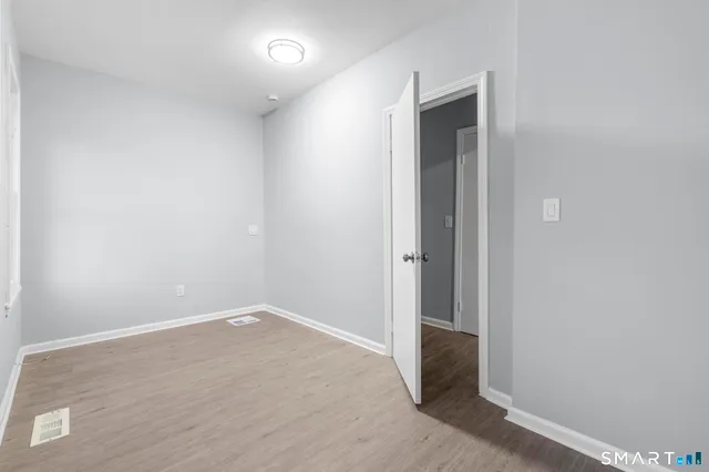 a view of an empty room with a window and wooden floor