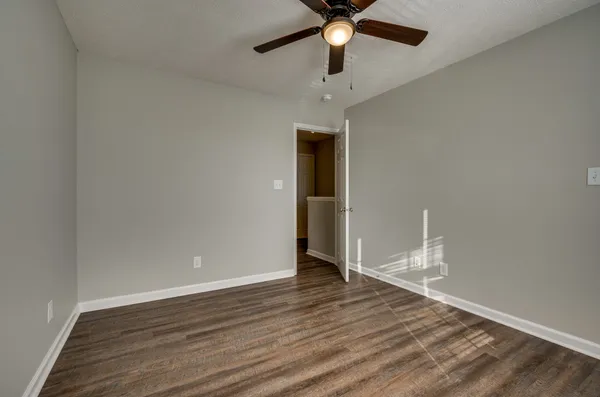an empty room with wooden floor and ceiling fan