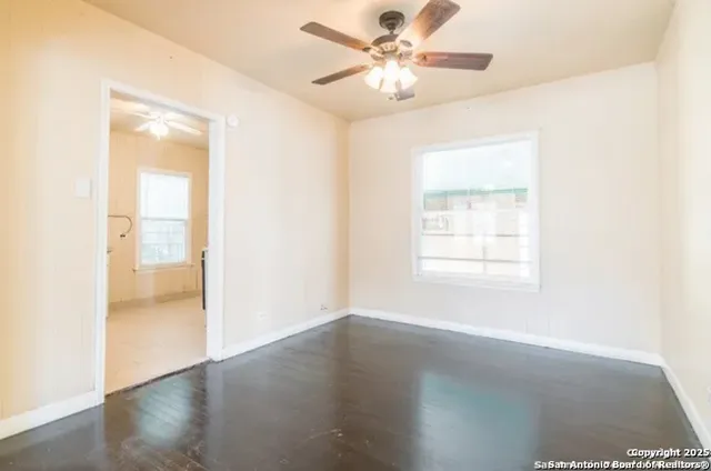a view of an empty room with wooden floor and a window