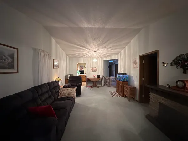 a living room with furniture a flat screen tv and a refrigerator