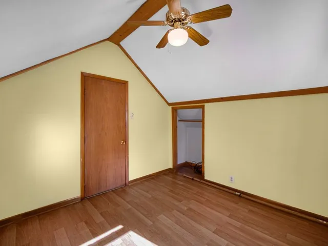 an empty room with wooden floor closet and fan
