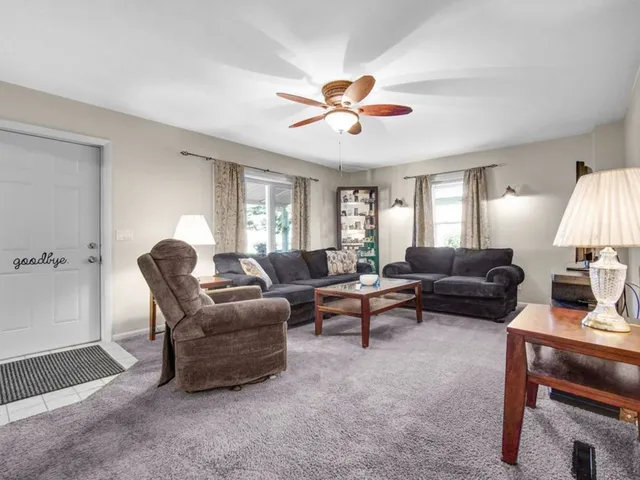 a living room with furniture a ceiling fan a lamp and a window