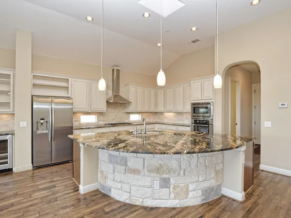 a view of a kitchen with kitchen island a counter top space a sink stainless steel appliances and cabinets