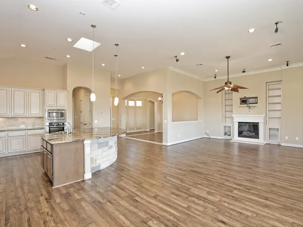 a large kitchen with granite countertop a stove top oven a sink a counter space and cabinets