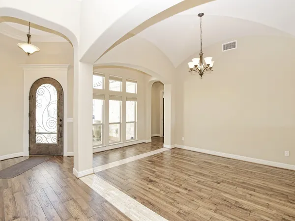 a view of an empty room with window and wooden floor