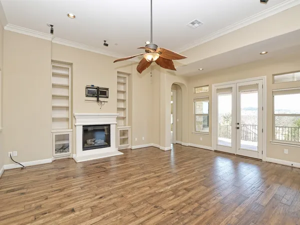a view of an empty room with window and wooden floor