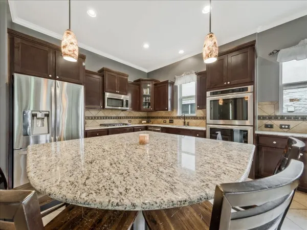 a large kitchen with stainless steel appliances kitchen island granite countertop a table chairs and a refrigerator