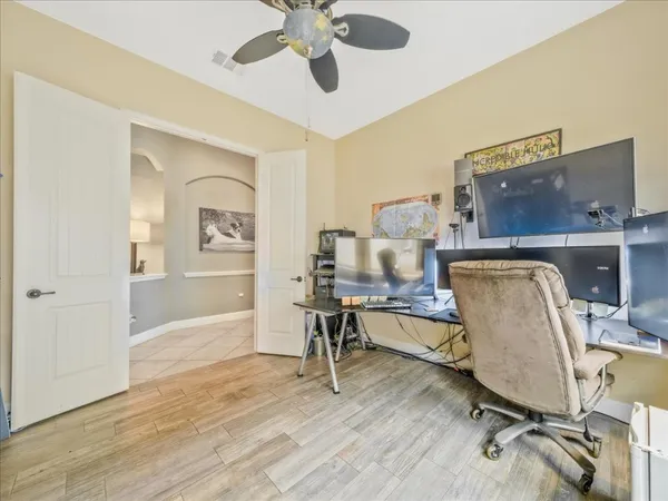 a view of a workspace with wooden floor and a ceiling fan