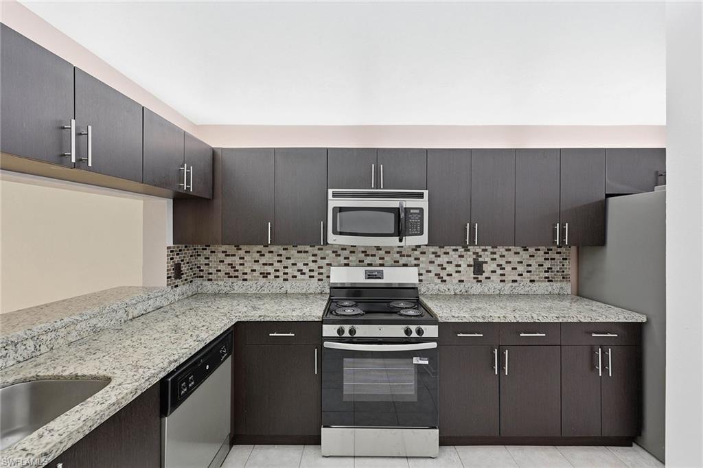 1231 Commonwealth Circle, Unit Q104 Naples, FL 34116 - Photo 14 of 33 a kitchen with granite countertop a stove and a sink