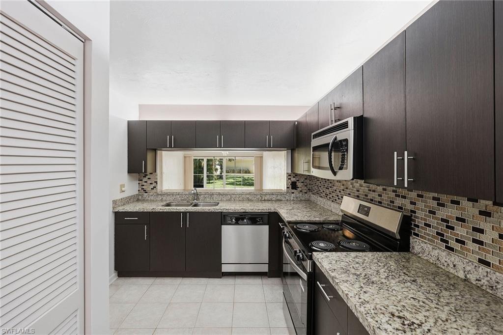 1231 Commonwealth Circle, Unit Q104 Naples, FL 34116 - Photo 15 of 33 a kitchen with stainless steel appliances granite countertop a stove and a sink