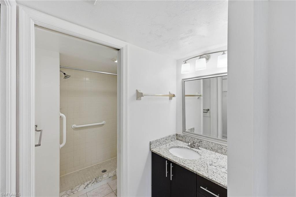 1231 Commonwealth Circle, Unit Q104 Naples, FL 34116 - Photo 22 of 33 a bathroom with a granite countertop sink and a mirror
