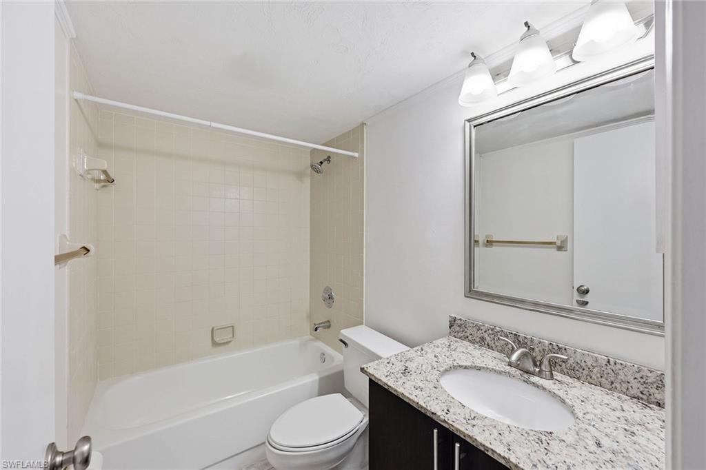 1231 Commonwealth Circle, Unit Q104 Naples, FL 34116 - Photo 26 of 33 a bathroom with a granite countertop sink toilet and shower