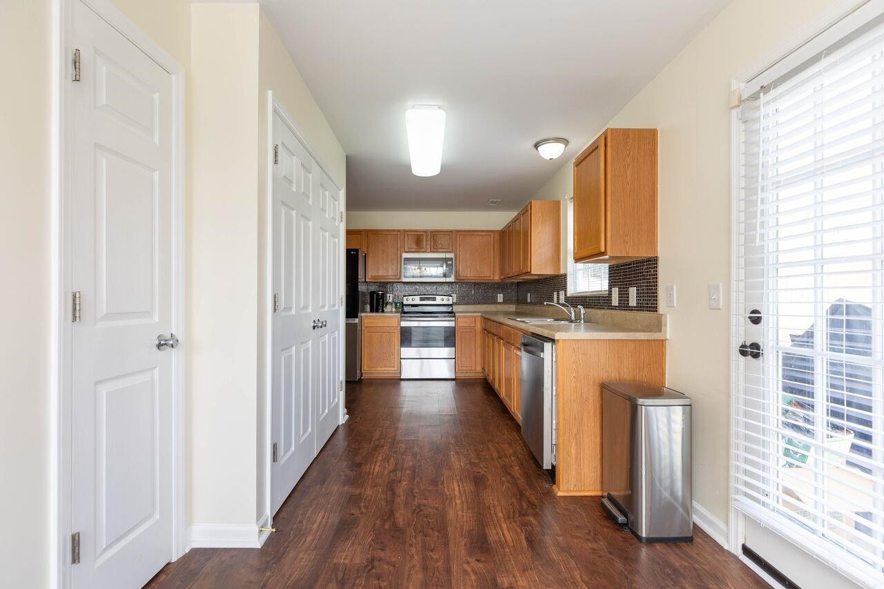 3409 Colossae Court Raleigh, NC 27610 - Photo 11 of 28 a kitchen with stainless steel appliances granite countertop a refrigerator a sink dishwasher a stove and white countertops with wooden floor