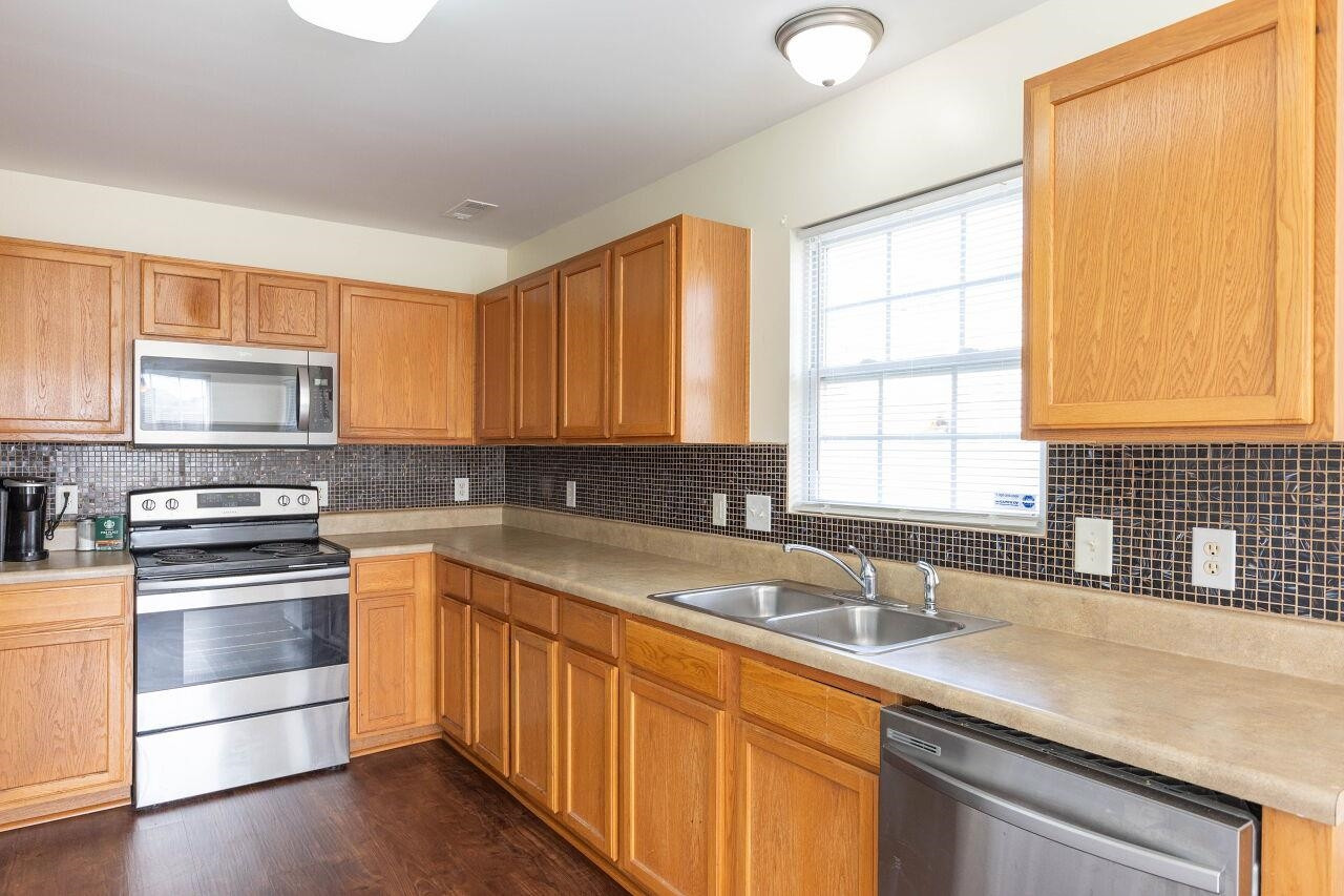 3409 Colossae Court Raleigh, NC 27610 - Photo 12 of 28 a kitchen with stainless steel appliances granite countertop a sink stove cabinets and wooden floor