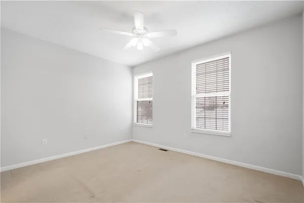 an empty room with chandelier fan and windows
