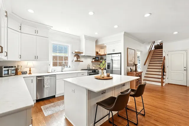 a kitchen with stainless steel appliances granite countertop a sink a stove and a wooden floors