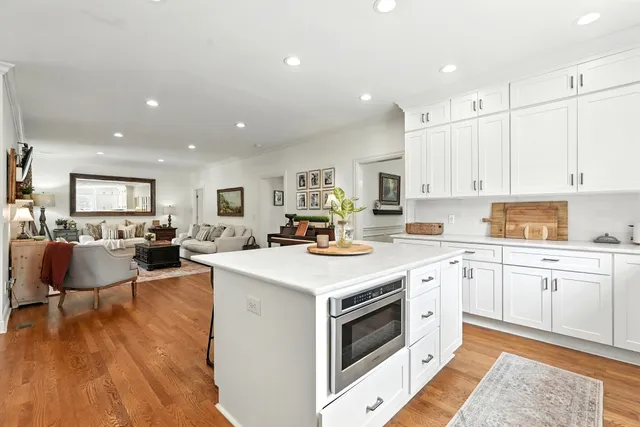 a kitchen with stainless steel appliances granite countertop a stove a sink a refrigerator and white cabinets with wooden floor