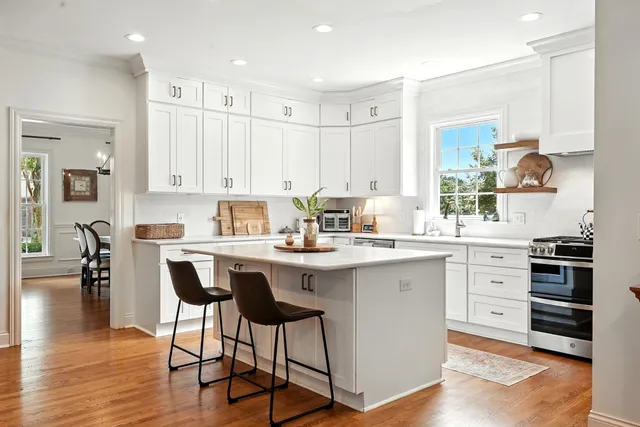 a kitchen with a sink stove and white cabinets with wooden floor