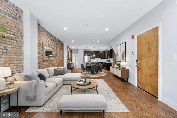 a living room with furniture kitchen view and a window