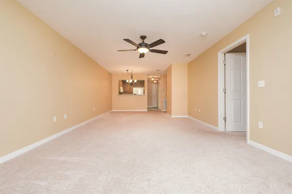 an empty room with chandelier fan and windows