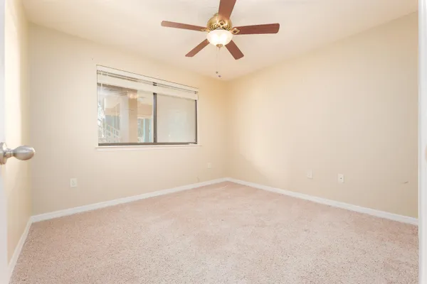 an empty room with a window and a fan