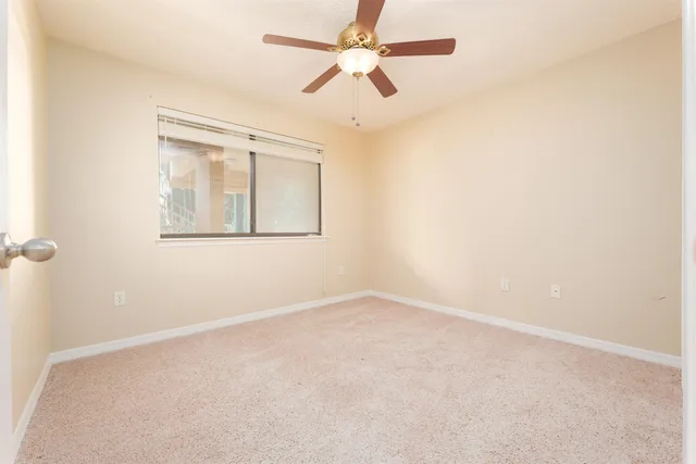 an empty room with a window and a fan