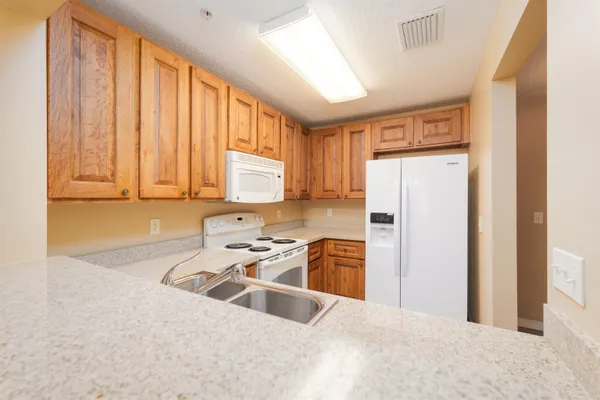 a kitchen with a refrigerator a stove top oven cabinets and a window