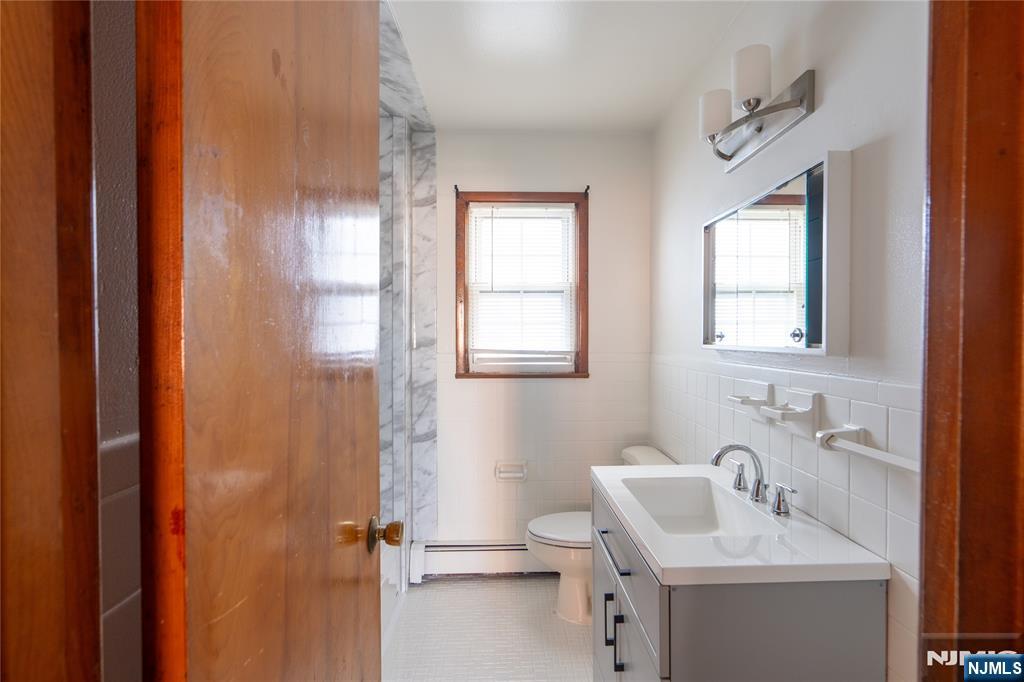 24 Mahar Avenue Clifton, NJ 07011 - Photo 19 of 20 a bathroom with a sink a toilet and a mirror