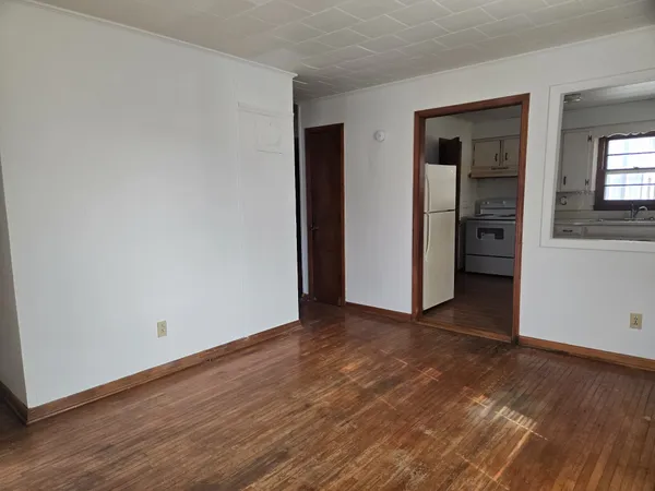 a view of an empty room with wooden floor and closet