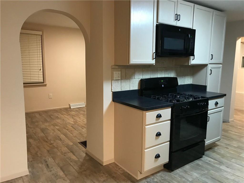 1520 1/2 4th Avenue Coraopolis, PA 15108 - Photo 5 of 20 a kitchen with stainless steel appliances granite countertop white cabinets and stove top oven with wooden floor