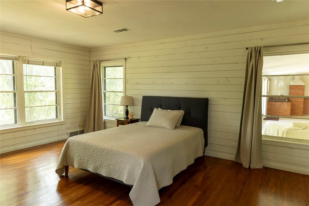 3228 Colcord Avenue Waco, TX 76707 - Photo 14 of 29 Room featuring warm-toned wood flooring, white horizontal plank wall finishes, and multiple windows providing natural light