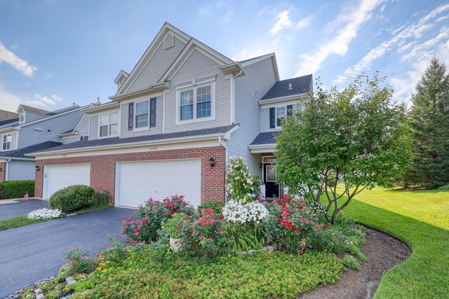 4579 Half Moon Drive, Unit D Yorkville, IL 60560 - Photo 1 of 44 a front view of a house with a yard and potted plants