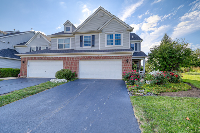 4579 Half Moon Drive, Unit D Yorkville, IL 60560 - Photo 2 of 44 a front view of a house with a yard and garage