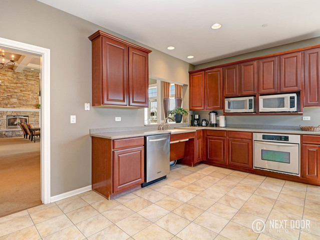 4579 Half Moon Drive, Unit D Yorkville, IL 60560 - Photo 35 of 44 a kitchen with stainless steel appliances granite countertop a stove sink and cabinets