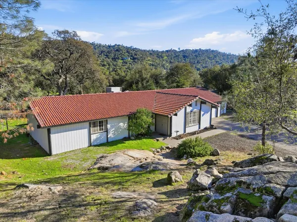 a view of a big house with a big yard plants and large trees