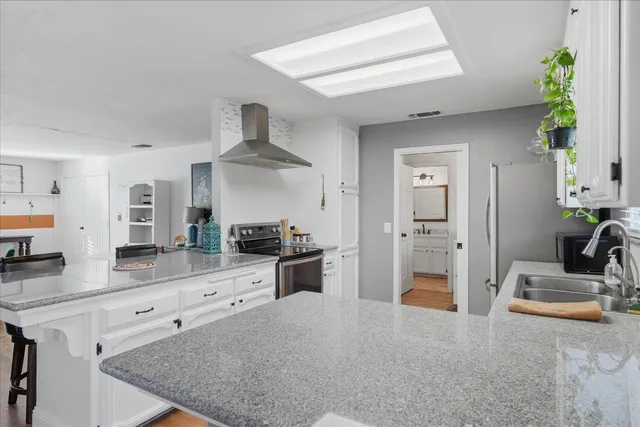 a kitchen with stainless steel appliances granite countertop a sink a stove and a refrigerator