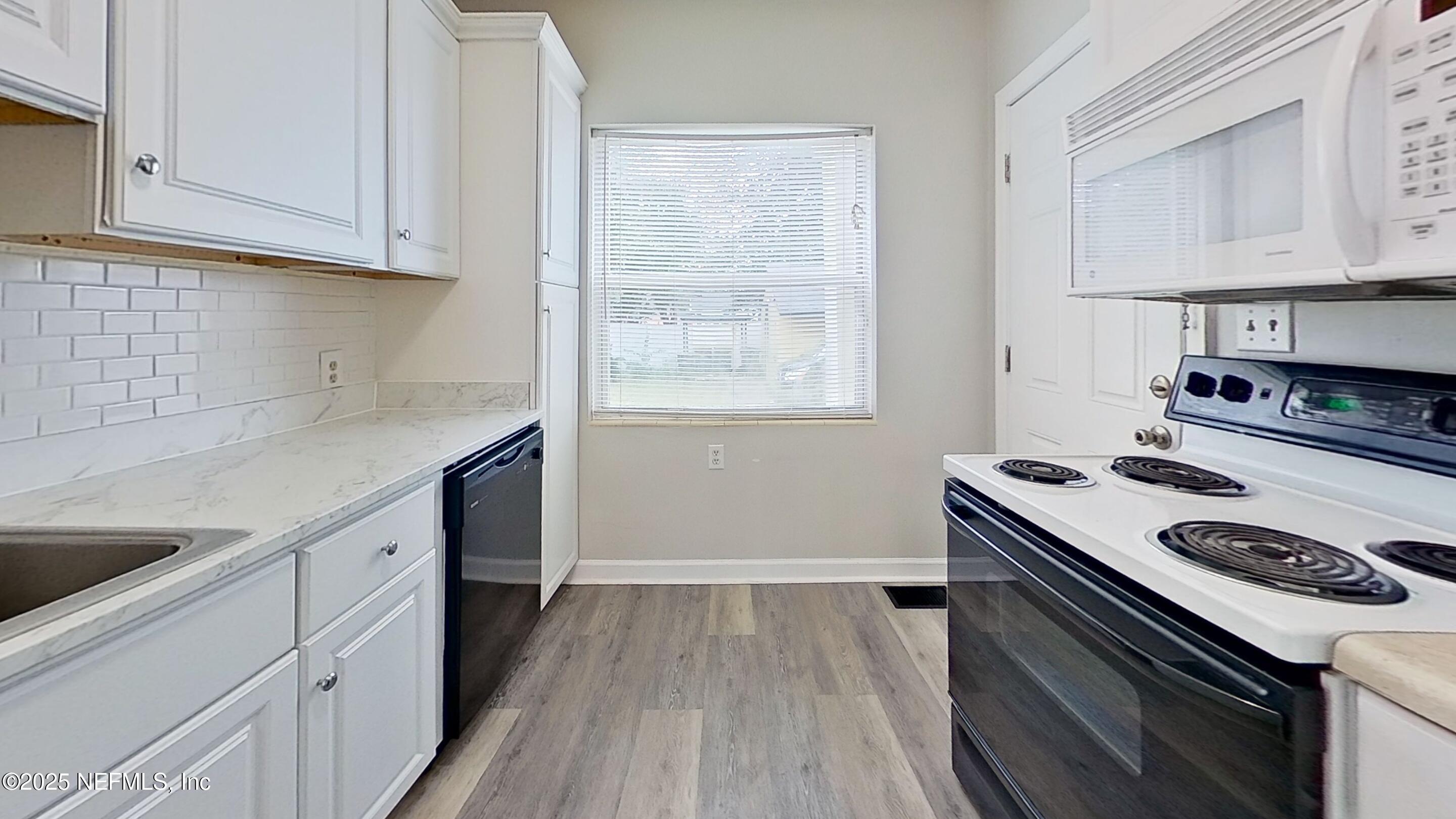 1543 Nicholson Road, Unit 1 Jacksonville, FL 32207 - Photo 9 of 16 a kitchen with a stove and white cabinets