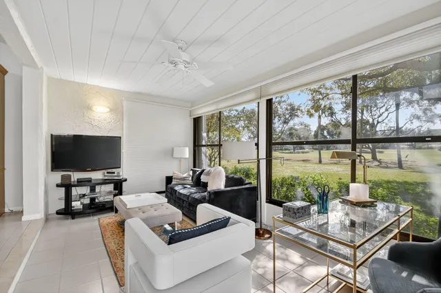 a living room with furniture a flat screen tv and a floor to ceiling window