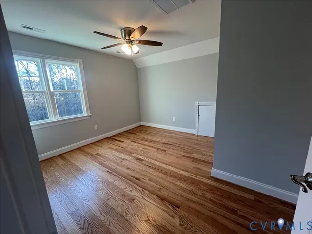 a view of an empty room with wooden floor and stairs