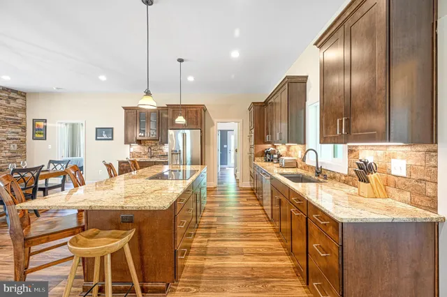 a large kitchen with stainless steel appliances granite countertop plenty wooden floors couches and large cabinets