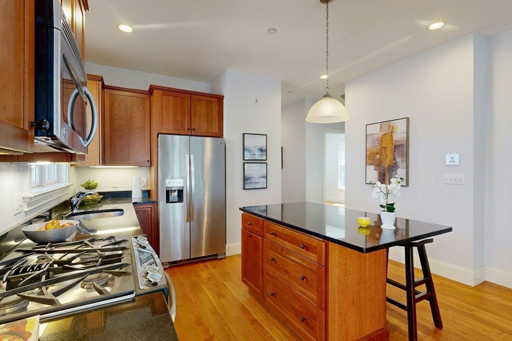 16 A Meehan Street, Unit 1 Boston, MA 02130 - Photo 7 of 16 a kitchen with stainless steel appliances granite countertop a stove refrigerator and a wooden floor